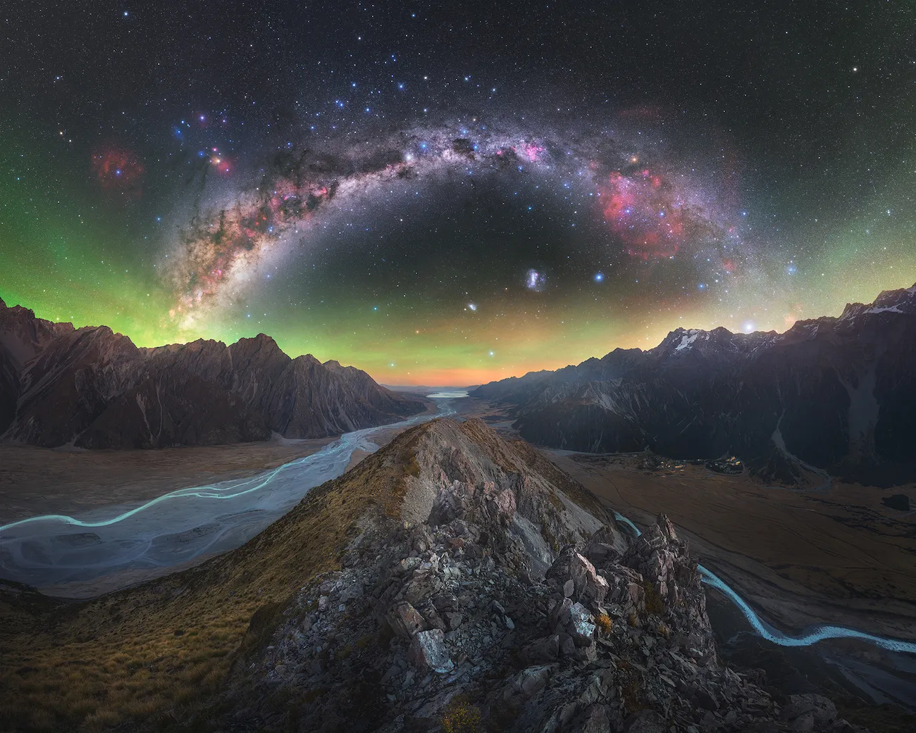 An image showing the Milky Way arching across the night sky above winding glacial rivers in AorakiMount Cook National Park New Zealand