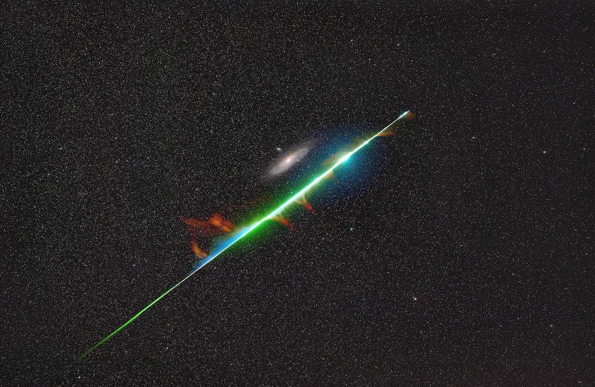 An image showing the Andromeda Galaxy with a bright fireball from the Perseid meteor shower streaking across the frame
